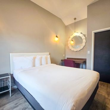 Cozy bedroom with white bed, wooden flooring, and stylish lighting.