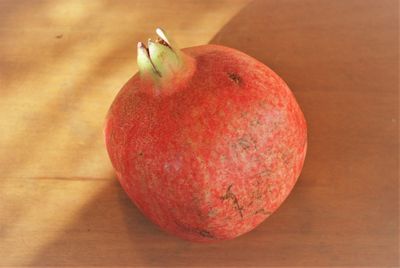 A whole pomegranate showing the crown-like shape of the blossom end.