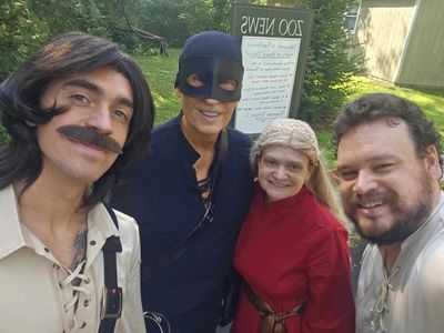 Four people in Renaissance-style costumes pose outdoors for a selfie.