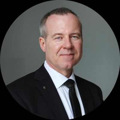 Professional man in a black suit and tie smiling.