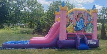 Inflatable pink and purple princess-themed bounce house with a slide outdoors.