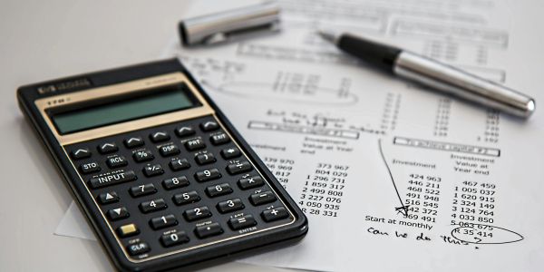 Calculator, pen, and financial documents on a desk.
