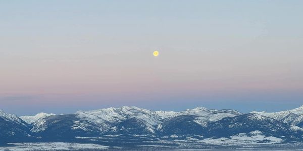A picturesque landscape featuring mountains, a lake, and a clear blue sky.