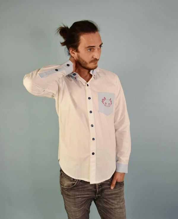 Mann vor hellblauem Hintergrund, eine Hand am Nacken und trägt weiß/ blaues Hemd mit Axolotl