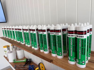 Multiple tubes of sealant lined up on a shelf.