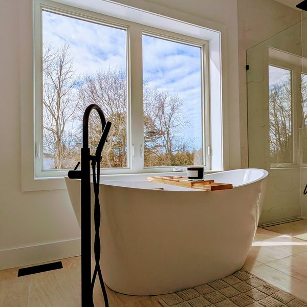 Modern bathroom with a freestanding tub and large window showing a scenic view.