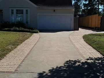 a concrete driveway with pave stone on each side