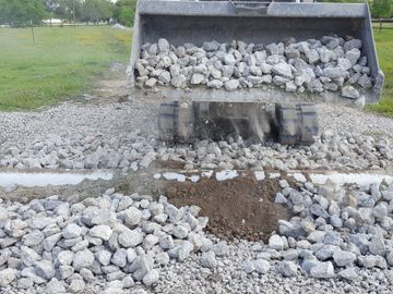 a skidsteer moving rocks for drainage