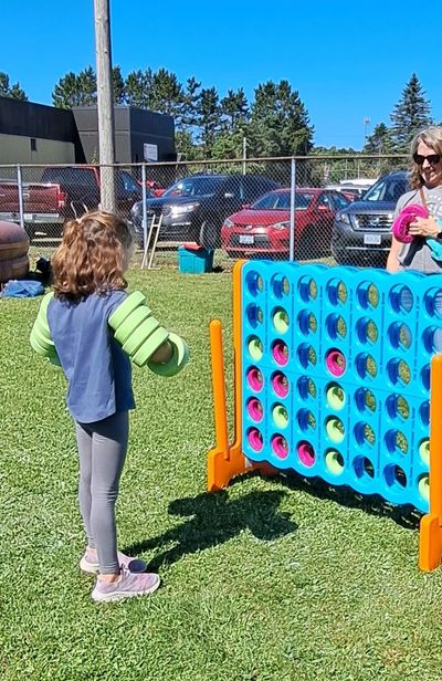 Mom and daughter playing giant Connect 4 at fall fair.