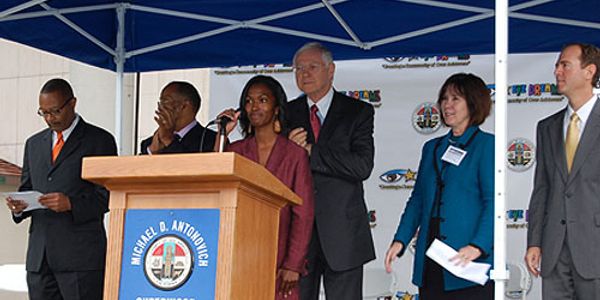 Group of diverse professionals at a podium under a tent during an event.