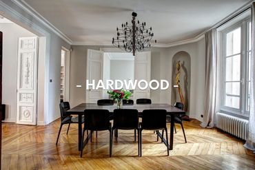 Elegant dining room with hardwood floors and modern black furniture.