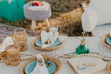 Elegant outdoor table setting with turquoise plates and woven placemats.
