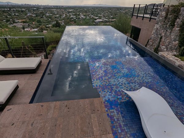 Infinity pool overlooking a sprawling cityscape under a cloudy sky.