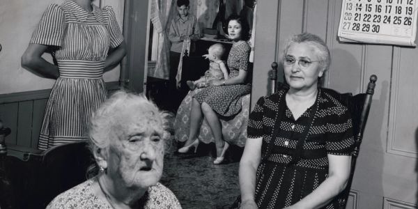 Black and white photo of multiple generations of women in a room.
