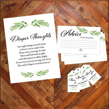 Baby shower cards and tags with green leaf designs on wooden background.