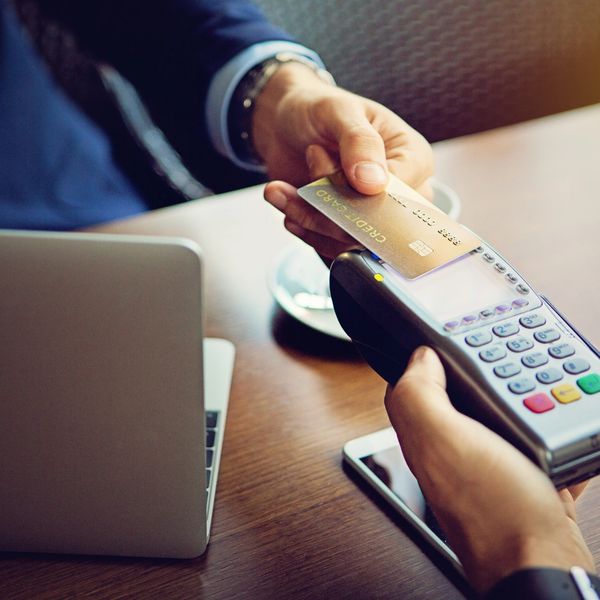 A person uses a credit card to pay at a point-of-sale terminal.