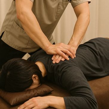 Therapist performing a deep back massage on a client lying face down.