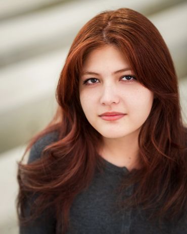 Portrait of a young woman with red hair and a calm expression.