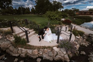 Newlyweds share a kiss on a circular concrete platform surrounded by nature.