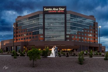Newlyweds share a tender moment outside Santa Ana Star Casino Hotel at dusk.