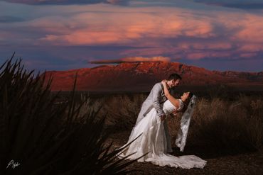 Bride and groom share a joyful moment at sunset with mountains in the background.