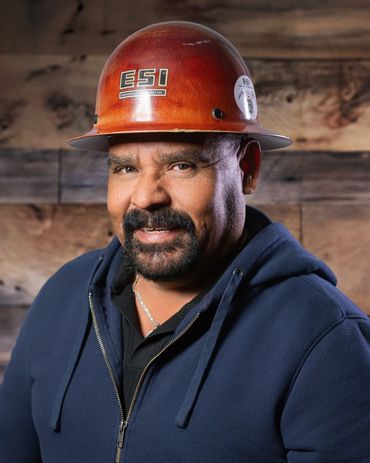 Smiling construction worker wearing an ESI hard hat and navy hoodie.
