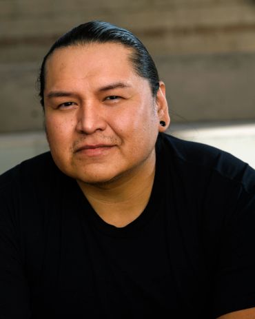 Portrait of a man with slicked-back hair and black shirt.