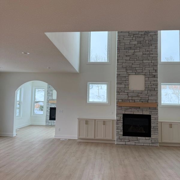 Bright living room with stone fireplace and large windows.