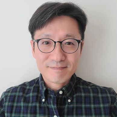 Man with glasses wearing a green and blue checkered shirt.
