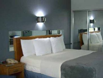 Guest room at the resort showing 1 bed with white pillows and grey comforter and a closet with mirro