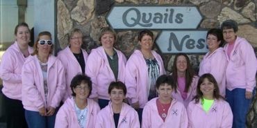 A group of ladies all wearing pink jackets in front of the Quails Nest sign