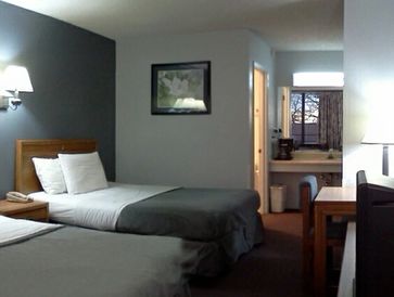 Guest room at the resort showing 2 beds with white pillows and grey comforter, a vanity and a desk