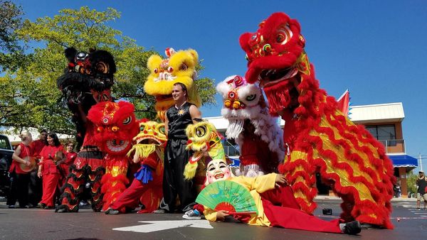 People with colorful lion dance costumes and a performer with a fan.