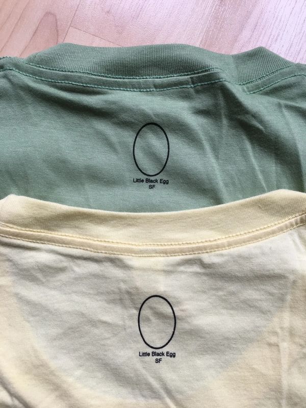 Neck prints of the Little Black Egg logo on two shirts