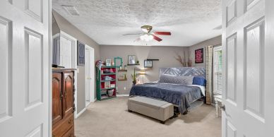 Cozy bedroom with blue bedding and ceiling fan.