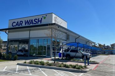 Modern car wash facility with blue canopies and clear skies.