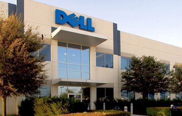 Exterior shot of a Dell office building with trees and bushes.