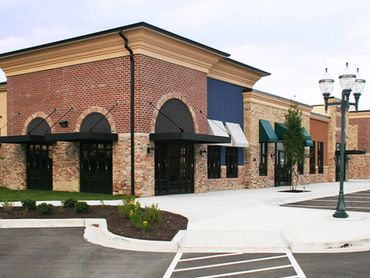 A modern strip mall with brick facades and empty parking spaces.