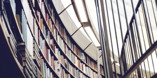 Curved library shelves filled with books under a skylight.
