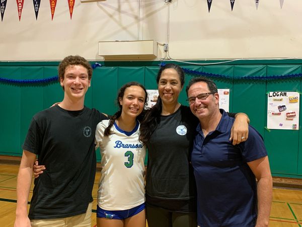 Family photo in a gymnasium after a volleyball game.