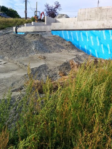 Construction site with concrete foundation and blue waterproofing.