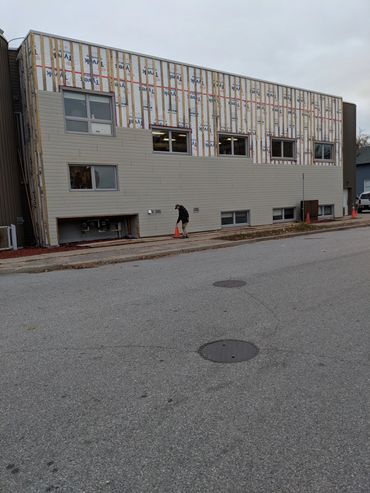 Building under construction with a person placing an orange cone on the sidewalk.