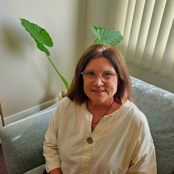 Smiling woman with glasses sitting on a couch.