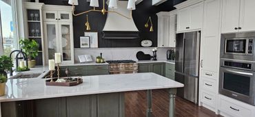 Modern kitchen with green cabinets, white countertops, and stainless steel appliances.
