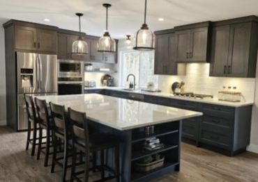 Modern kitchen with dark cabinets, large island, and stainless steel appliances.