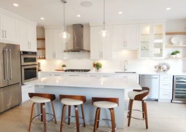 Bright modern kitchen with white cabinetry and a large island with stools.