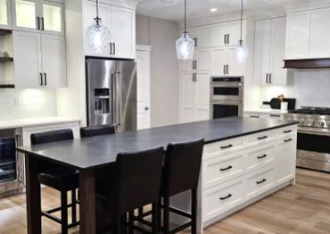 Modern kitchen with a large island and black chairs.