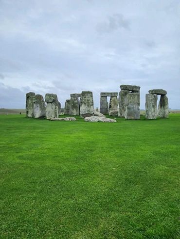 Stonehenge, ancient standing stones on a green field under a cloudy sky.