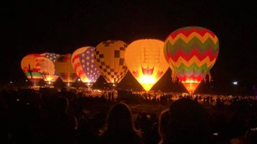 Hot air balloons glowing brightly at night during a festival.