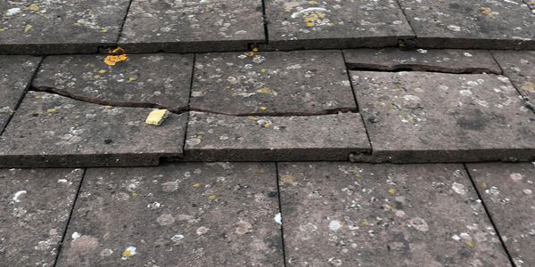 Old roof tiles with cracks and moss growth.